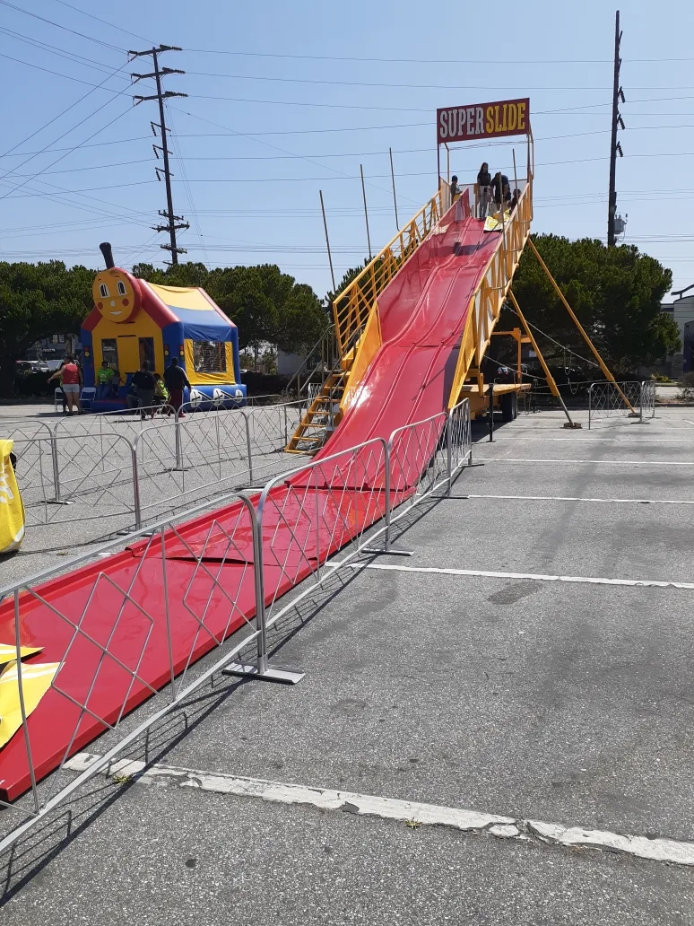 A trackless train loaded with young riders completing a loop at a community park event in Carson, with parents watching from a roped perimeter