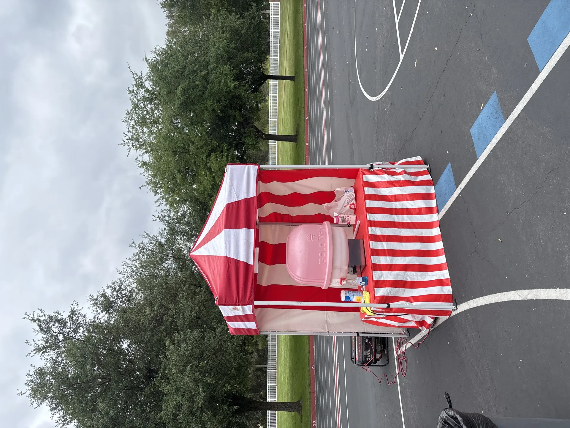 A carnival birthday setup with cotton candy, popcorn, and a striped game booth arranged on a residential patio